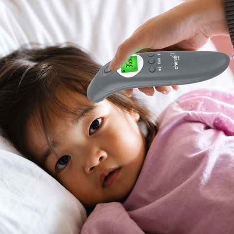 Child lying down with a digital thermometer held near their forehead