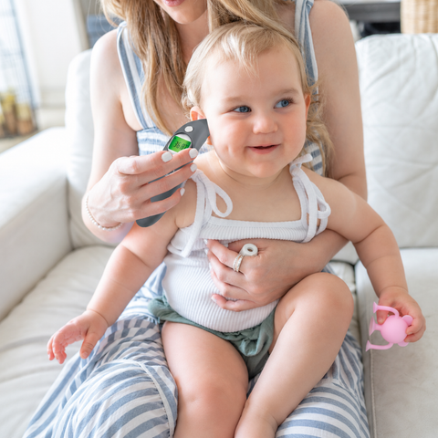 Baby being measured with a growth chart by a woman on a couch