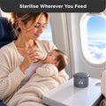 Mother bottle-feeding her baby during a flight, with a portable bottle warmer on the tray table beside them.