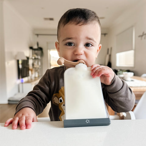 Reusable silicone food pouch being used by a baby during mealtime.