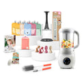 A baby feeding and cleaning kit displayed on white circular pedestals against a white background. The set includes a white baby blender with colorful food inside, multiple silicone feeding spoons in pink, beige, and brown, two cleaning brushes with orange handles, a pink bottle, a card of mini cloths, a packaged organizer, and other accessories.